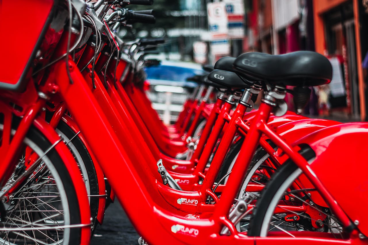 hero-img-01 Rows of bright red bicycles parked in a bustling São Paulo street.